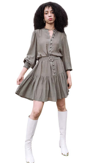 Woman wearing a gray dress with a belt and white knee-high socks on a white background