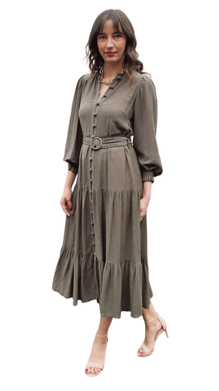 Woman wearing a long olive green dress with a belt on a white background